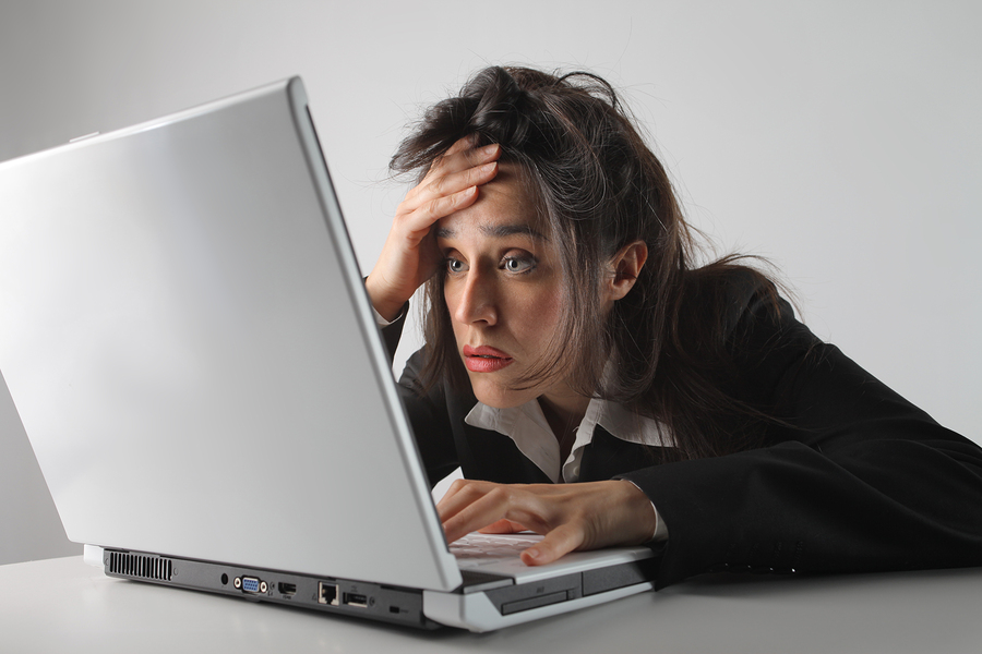 A frusterated business woman in front of a laptop making a face